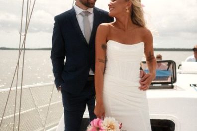 Bride and groom on a boat with a U.S. flag in the background.